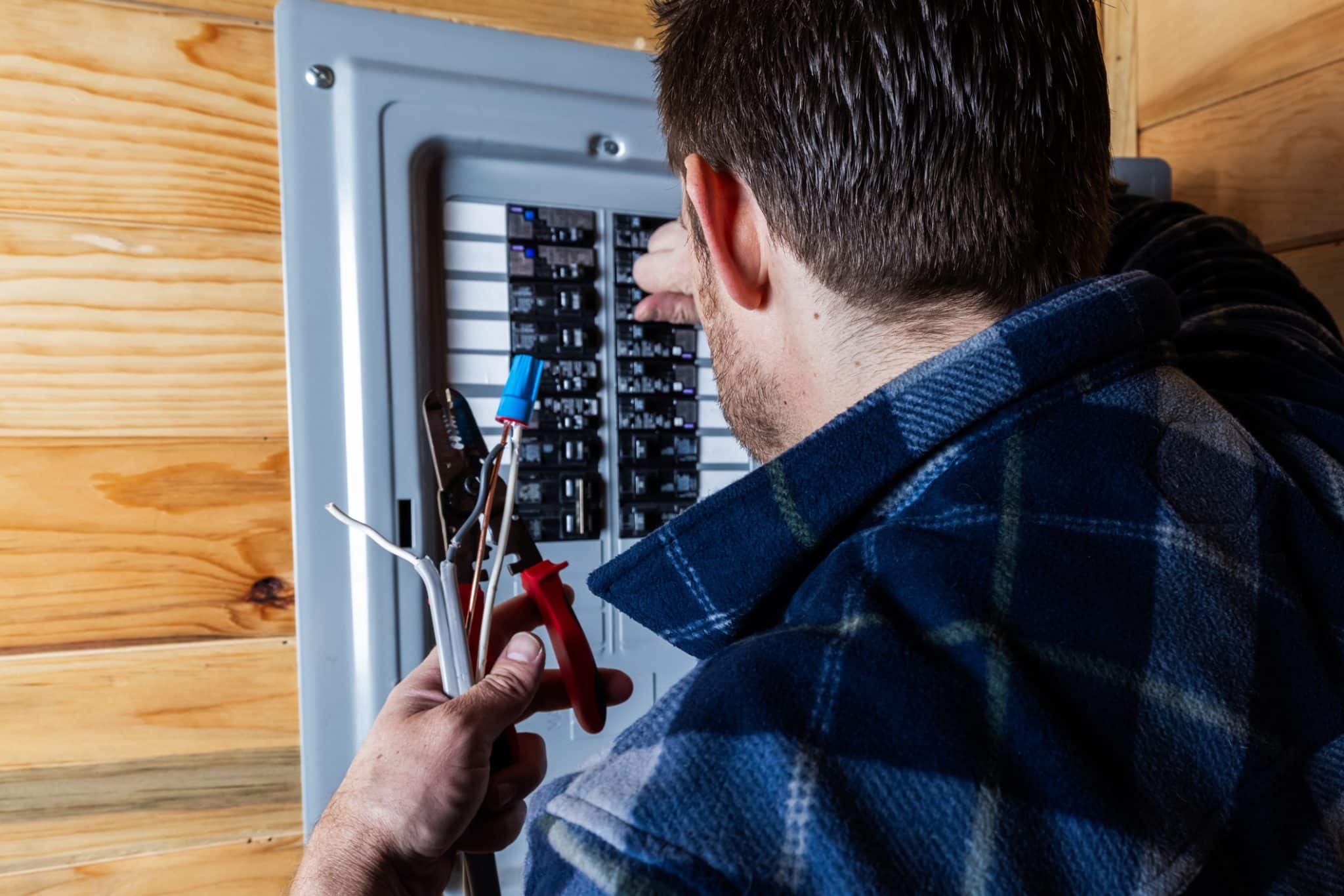 Electrician installing wiring in a residential electrical panel during a home electrical panel upgrade.