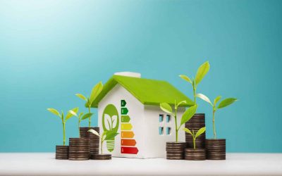 A miniature house with an energy efficiency rating chart surrounded by stacked coins with green seedlings growing from them